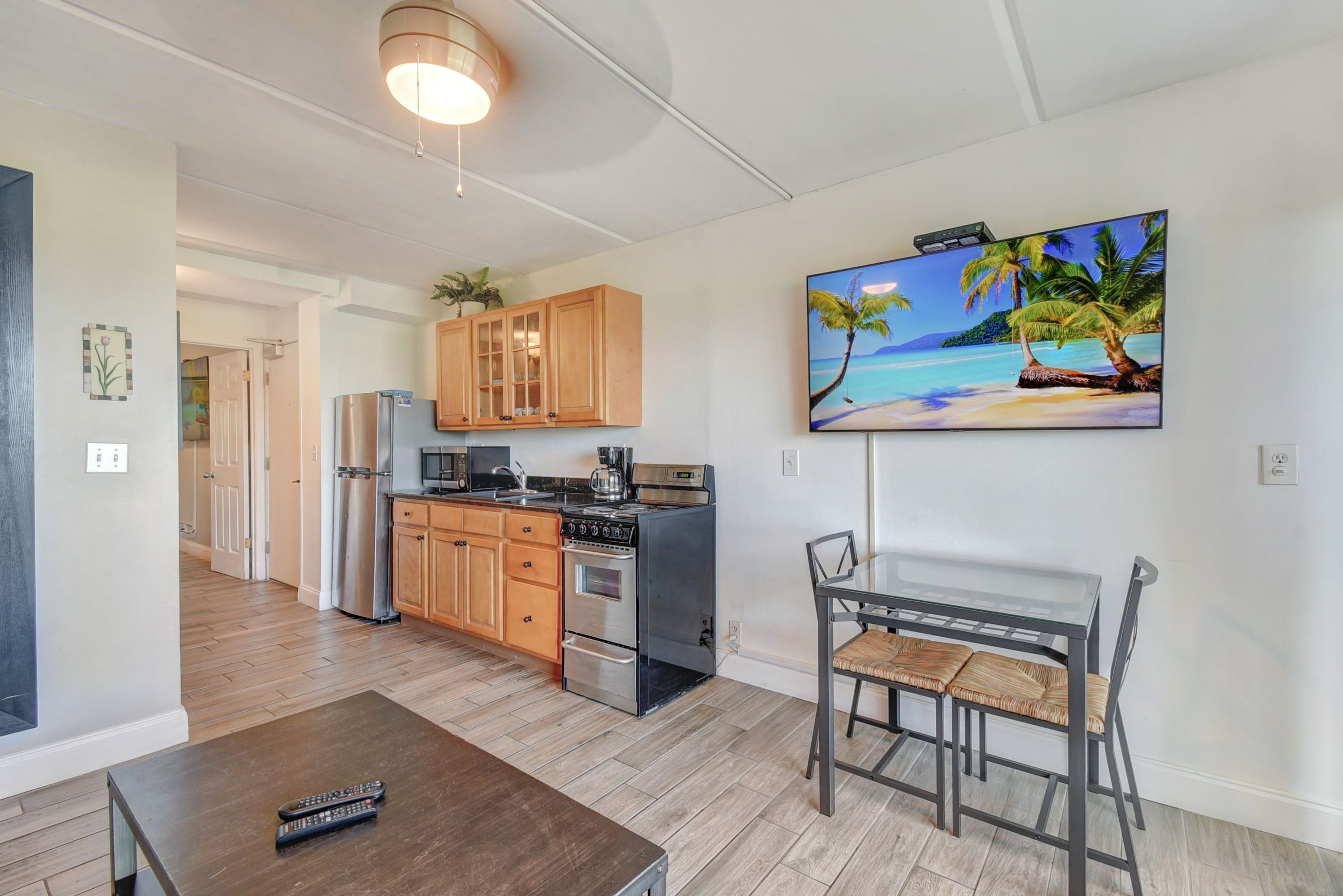 A modern kitchen with wooden cabinets, stainless steel appliances, and a dining area with a glass table and chairs.