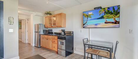 A modern kitchen with wooden cabinets, stainless steel appliances, and a dining area with a glass table and chairs.