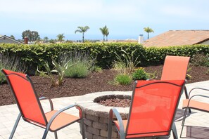 An outdoor seating area with two orange chairs and a stone fire pit.