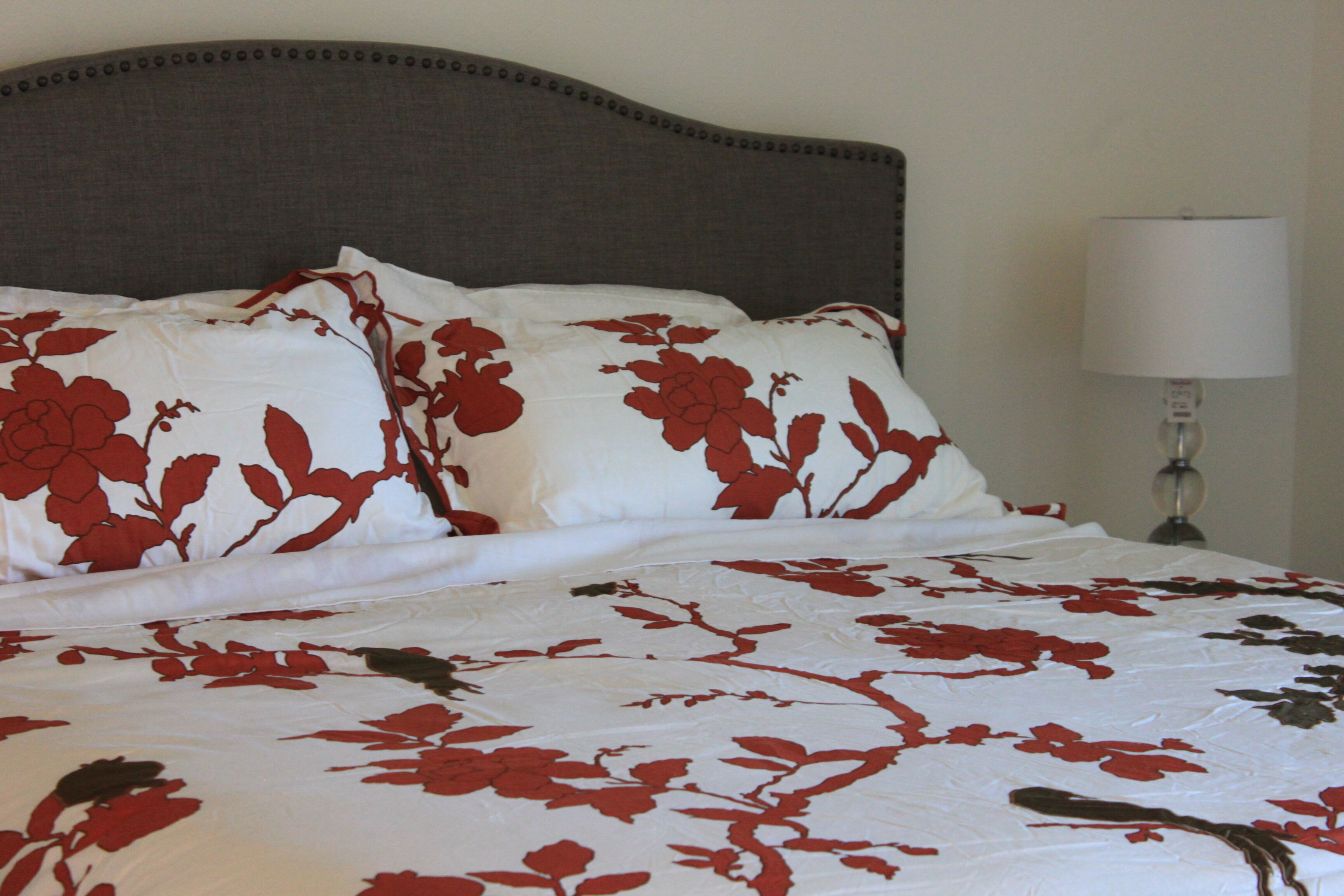 Un lit avec une couvre-lit à motifs floraux et des coussins assortis.