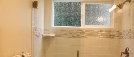 A bathroom with a glass-enclosed shower, a toilet, and a sink.