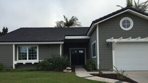 Una casa a due piani con rivestimento grigio scuro, un portico e un garage.