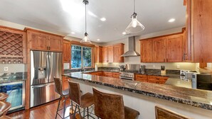 Una cocina moderna con armarios de madera, electrodomésticos de acero inoxidable y una isla grande con taburetes de bar.