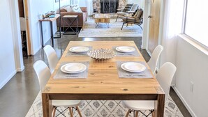 A dining area with a wooden table set for four, surrounded by white chairs. - Stunning Views: Rockwood Hill House (Joshua Tree)