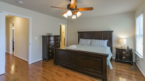 Une chambre à coucher avec un lit en bois, un ventilateur de plafond, une commode et une table de chevet.