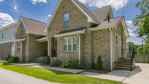 Une maison à deux étages avec une façade en briques, un porche à l’avant et un petit jardin devant.