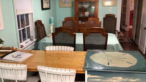 A dining area with a wooden table, four chairs, a cabinet with glass doors, and a window with blinds.