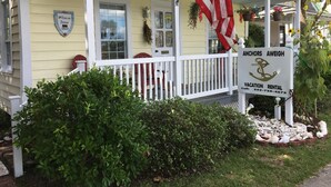 A vacation rental property with a porch, American flag, and a sign indicating it's an Anchor's Aweigh.