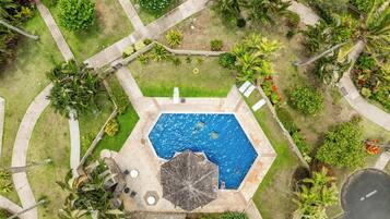 Vue aérienne d’une propriété résidentielle dotée d’une piscine, de mobilier de jardin et d’un espace vert environnant.