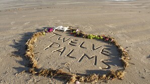 A sandy beach with the words "TWELVE PALMS" written in the sand, surrounded by small flowers and seaweed. - Twelve Palms-Pet Friendly, Golf Cart Zone, Close to Beach, Downtown, City Pool  (Port Aransas)
