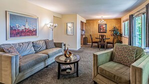 A living room with a sofa, armchair, coffee table, and a dining area with a table and chairs.