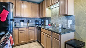 A kitchen with wooden cabinets, a black refrigerator, a sink, and a dishwasher.