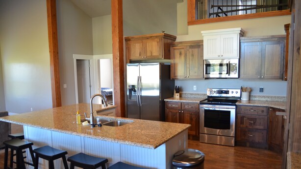 A kitchen with a large island, stainless steel appliances, wooden cabinets, and a trash can. - PERFECT LOCATION-Walking distance to beach, restaurants, pickleball, activities! (Garden City)