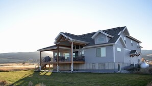 A two-story house with a covered porch, a large deck, and a view of the surrounding landscape. - PERFECT LOCATION-Walking distance to beach, restaurants, pickleball, activities! (Garden City)