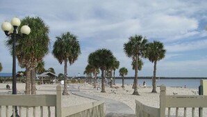 Un sentiero che conduce a una spiaggia con palme e una recinzione.