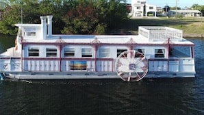 A riverboat with a large wheel, multiple decks, and a covered upper deck.