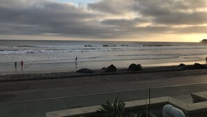 Une vue sur la plage, avec des vagues, une cÎte rocheuse et une jetée au loin.