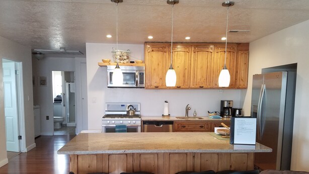 A modern kitchen with wooden cabinets, stainless steel appliances, and a central island with bar stools. - Private 2 Bedroom/ 2 Bath Home, close to Zion National Park (La Verkin)