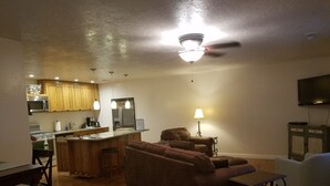 A living room with a brown sofa, a dining table, and a kitchen area with wooden cabinets and a refrigerator. - Private 2 Bedroom/ 2 Bath Home, close to Zion National Park (La Verkin)