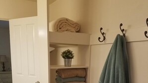 A room with a wooden bench, a white door, and a shelf with folded towels and a potted plant. - Private 2 Bedroom/ 2 Bath Home, close to Zion National Park (La Verkin)