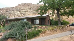 A single-story brick house with a sloped roof, a front porch, and a stone retaining wall. - Private 2 Bedroom/ 2 Bath Home, close to Zion National Park (La Verkin)