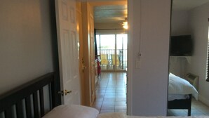 A hotel room with a bed, a TV mounted on the wall, and a balcony with chairs.