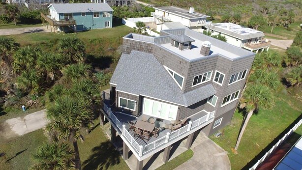 A multi-story house with a balcony, surrounded by palm trees and other vegetation. - AVAIL LABOR DAY WKEND - Steps to Beach - 3BR/3BA - Sleeps 8 - Garage (Palm Coast)