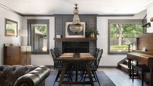 Un comedor con chimenea, un piano y un sofá de cuero.