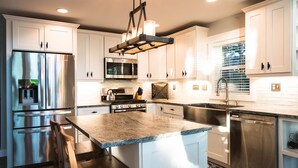 A modern kitchen with white cabinetry, stainless steel appliances, and a granite countertop.