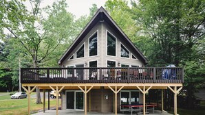 A two-story building with a balcony, a covered patio area, and a table tennis table.