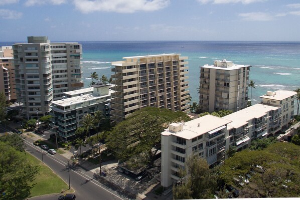 A high-rise building complex with multiple balconies overlooking a coastal area.