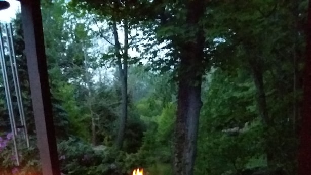 A table with two bottles, a glass, and a lit candle.