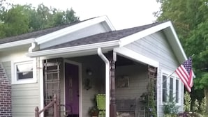 A house with a porch, a staircase, and a garden with pink flowers.