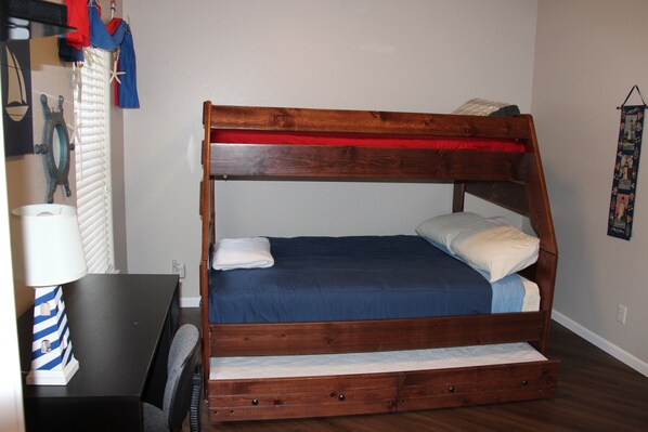 A bunk bed with a wooden frame, a blue mattress, and a red headboard.