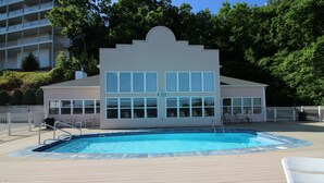 A swimming pool with a deck, a building with a number '202' sign, and a white fence. - Emerald Bay Condos Lake Ozark MO (Lake Ozark)