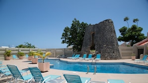 Un espace piscine avec des chaises longues bleues et une structure en pierre.