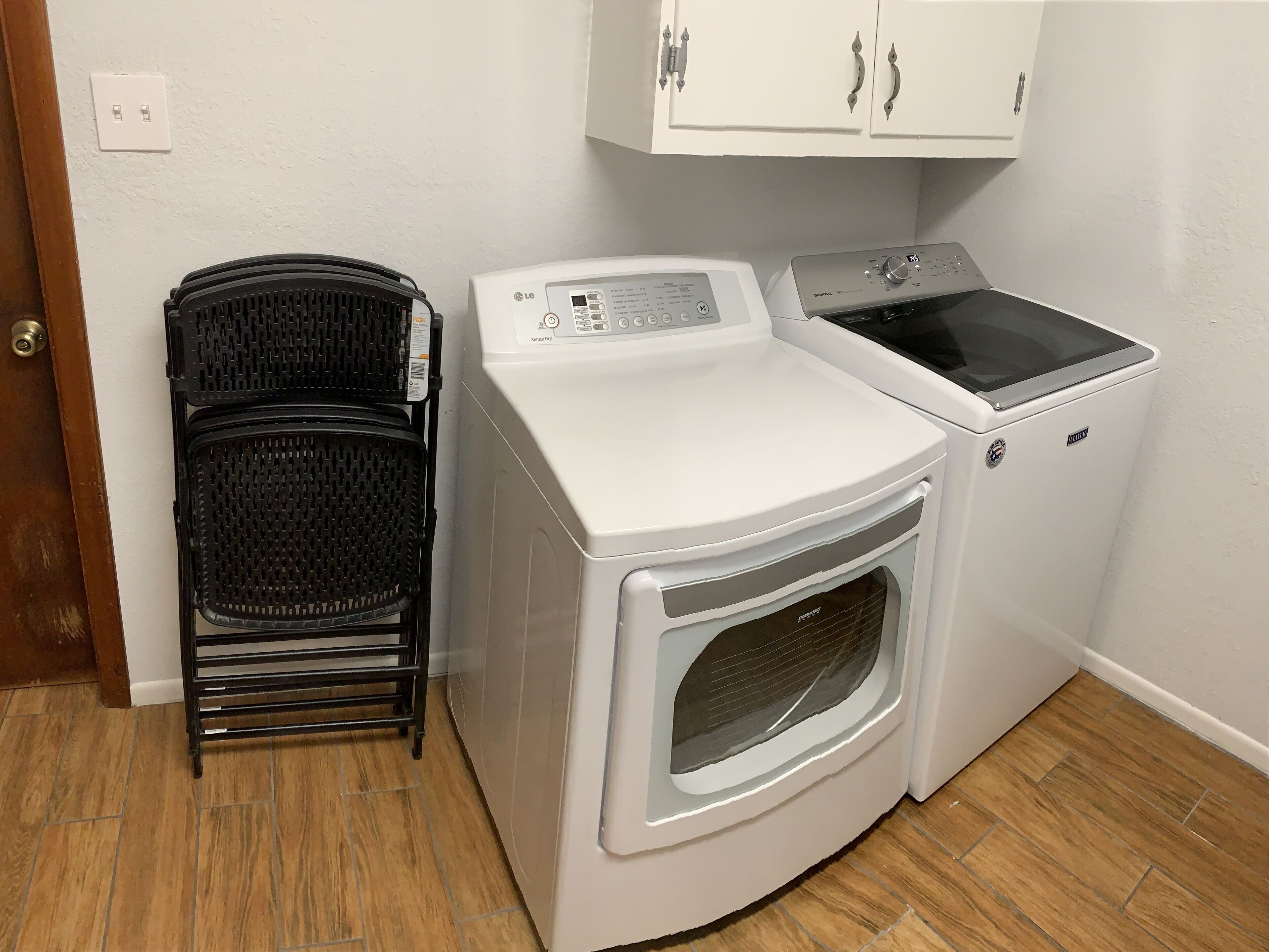 A laundry room with a stacked washer and dryer, a drying rack, and a cabinet above.