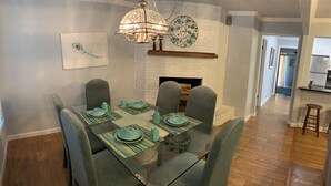 A dining area with a glass table, blue chairs, and a chandelier.