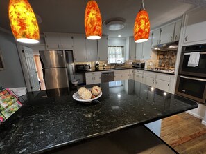 A modern kitchen with granite countertops, stainless steel appliances, and pendant lighting. - The Peacock House for animal lovers. Prime location! Near main attractions. (San Antonio)