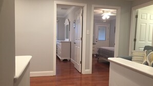 A hallway with wooden flooring leading to a bedroom with a bed and a window. - Great Location / Walk to Everything!  4BR Big Backyard (Beach Haven)