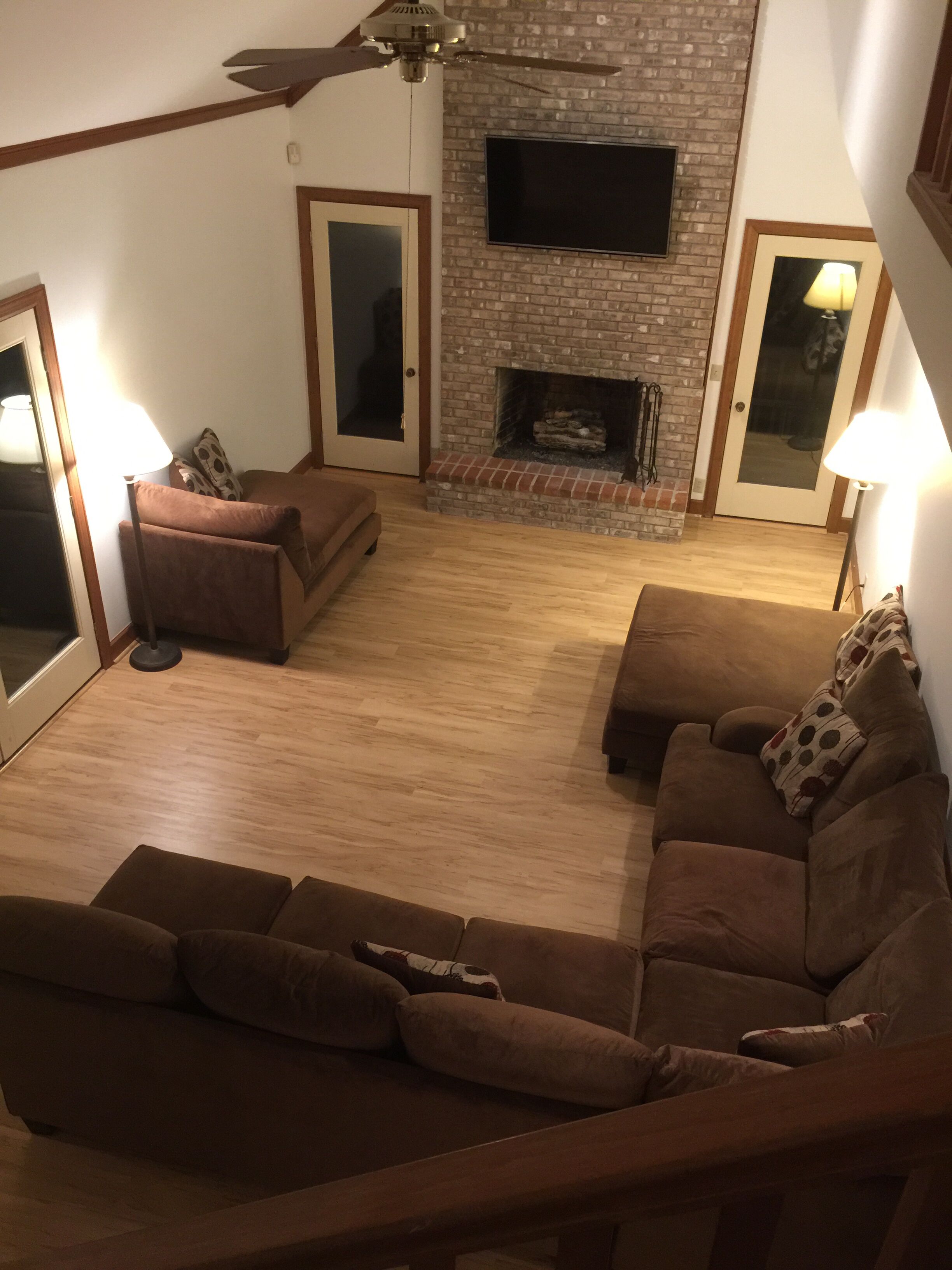 Una sala de estar con chimenea, dos sofás y un ventilador de techo.
