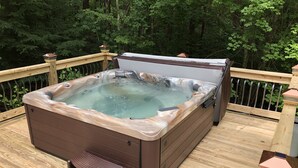 Un bain à remous sur une terrasse en bois, entouré d’arbres.