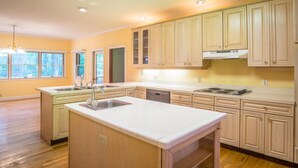 Une cuisine spacieuse avec des meubles en bois, un îlot central et une cuisinière intégrée.