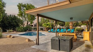 A covered outdoor area with a pool, lounge chairs, and a table. - Private Resort on 3/4 Acre Game Room Putting Green (Phoenix)