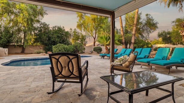 A covered outdoor area with a pool, lounge chairs, and a glass table. - Private Resort on 3/4 Acre Game Room Putting Green (Phoenix)