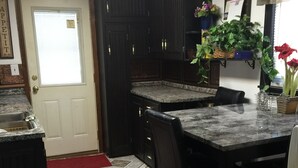 A kitchen with dark wooden cabinets, a marble countertop, and a dining table with chairs. - Main Floor 2 bedroom, 1 bath, Easy Walk to Mayo Clinic, trails, parks, shopping (Rochester)