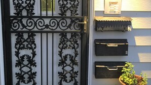 A black ornate metal gate with a glass panel, a mailbox with the number 319, and a potted plant on a small white table. - Main Floor 2 bedroom, 1 bath, Easy Walk to Mayo Clinic, trails, parks, shopping (Rochester)