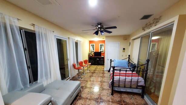 A hotel room with a bed, a sofa, a ceiling fan, and a tiled floor. - House For Big Family and a group of Friends . (Sarasota)