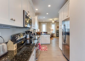 A modern kitchen with stainless steel appliances, white cabinetry, and a central island.