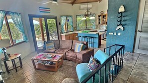 A spacious living area with a sofa, coffee table, and a staircase leading to an upper level. - AMAZING OCEAN VIEWS! "House in the Sky" Monte Paraiso (Playa Hermosa)